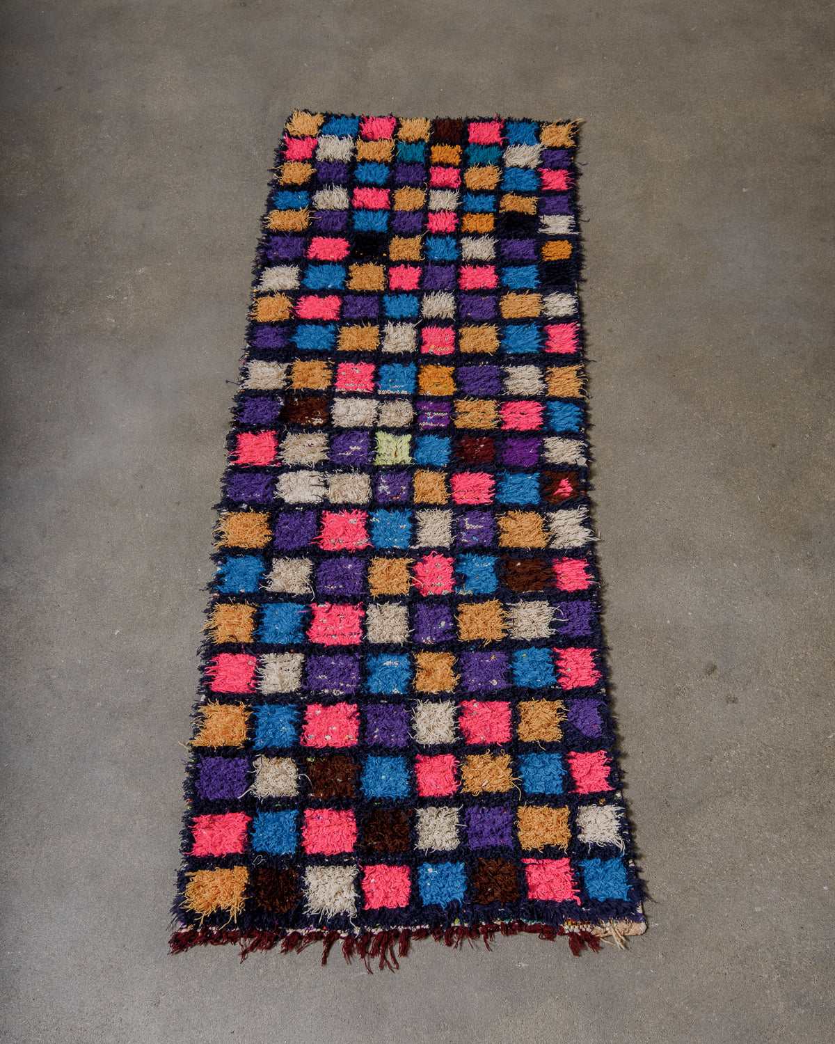 Multicoloured checkered rug on a concrete floor